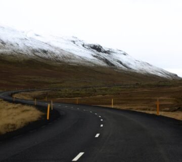Carretera sinuosa en Islandia con montañas nevadas y paisaje abierto