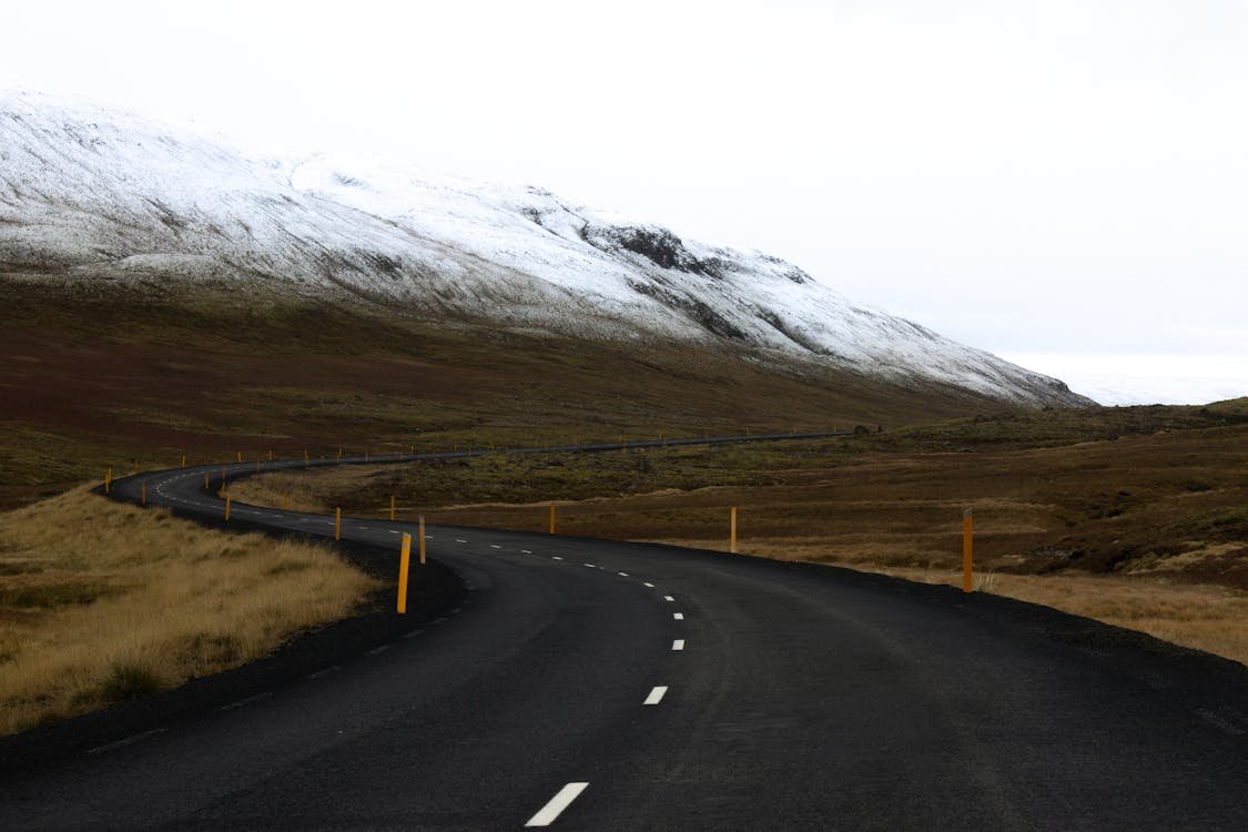 Carretera sinuosa en Islandia con montañas nevadas y paisaje abierto